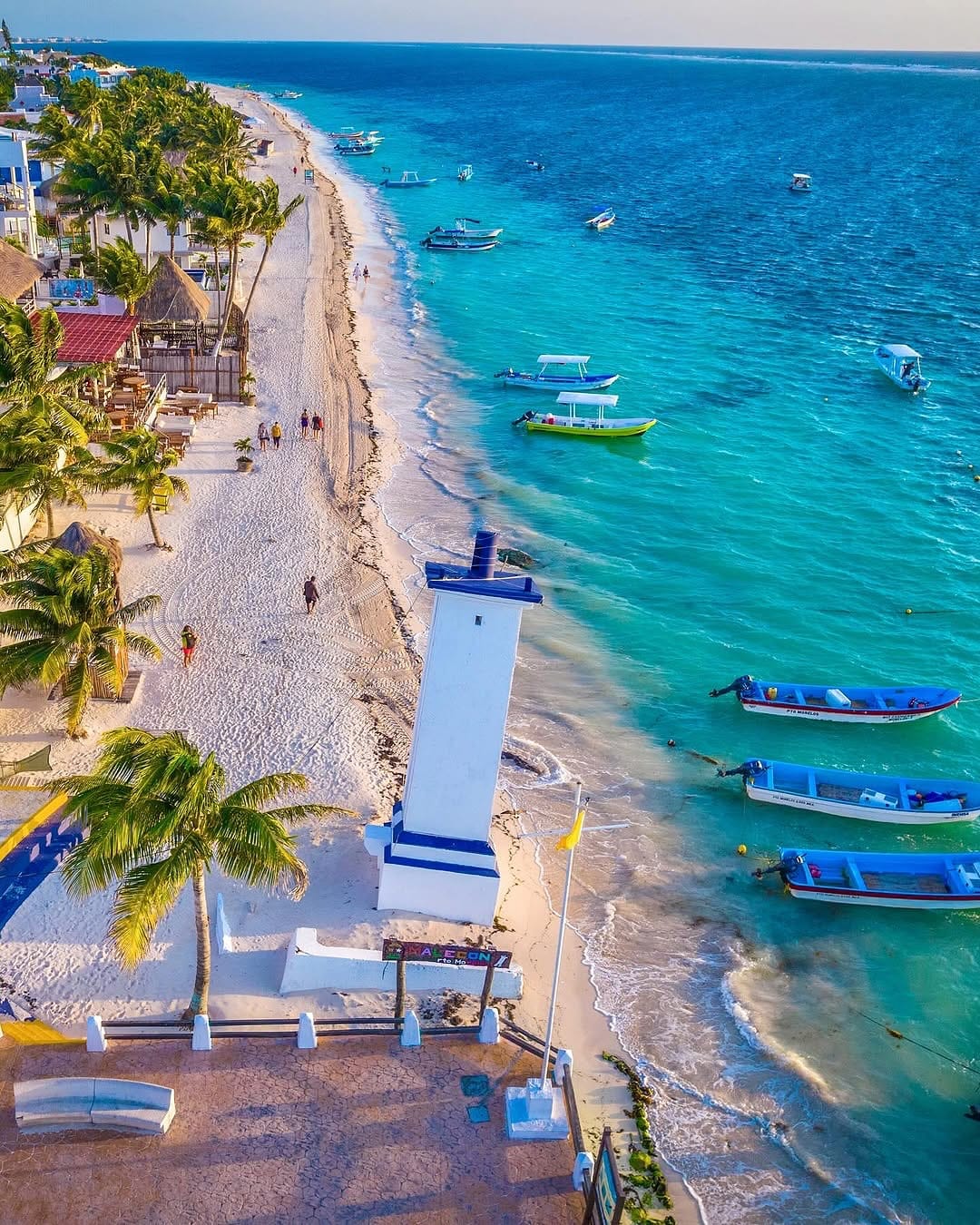 Faro y lanchas pesqueras en la playa de Puerto Morelos, Quintana Roo